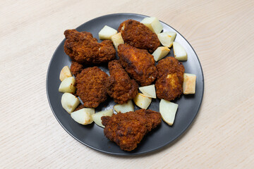 A plate of fried chicken with potato.