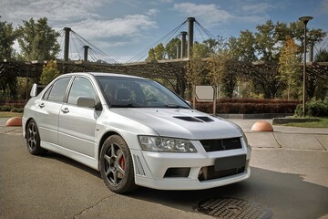 Naklejka premium White car on a street background. Modern city sport car with a spoiler wallpaper