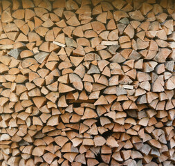 Firewood stacked near the wooden wall of old hut. Many chopped logs of firewood close up