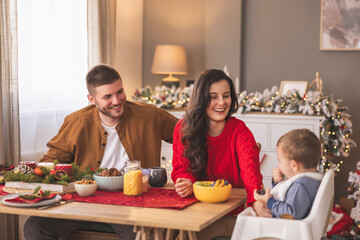 Parents spending Christmas day at home with baby, giving him fruit snack