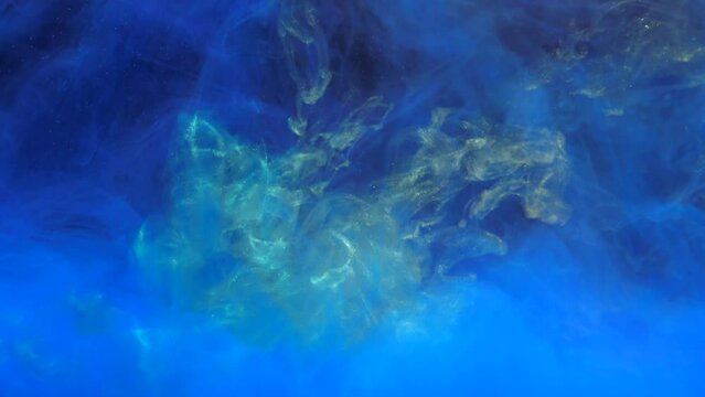 Slow motion gold yellow ink mixing in water with blue ink, swirling softly underwater. Slowmotion Colored acrylic cloud of paint isolated. Abstract smoke explosion animation. Beautiful art background