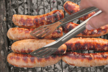 Grilled sausages. Cook man preparing grilling food bbq. Barbecue with smoke, flame outdoors. Tasty...