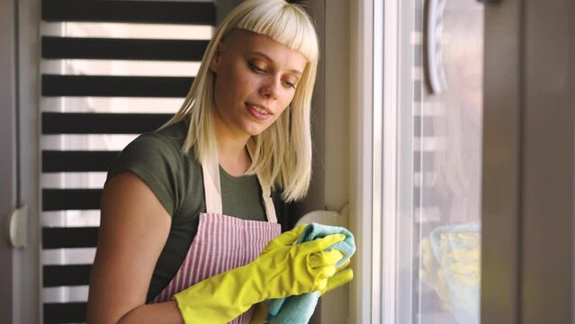 Young blonde woman cleaning windows