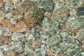 Clear sea water and stones on the rocky Mediterranean coast abstract background