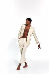 Naklejka premium appealing sexy african american man in elegant suit in motion on white backdrop, fashion concept
