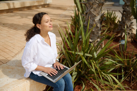 Mixed race young adult student in white shirt and casual denim, online studying on laptop. People. Online education