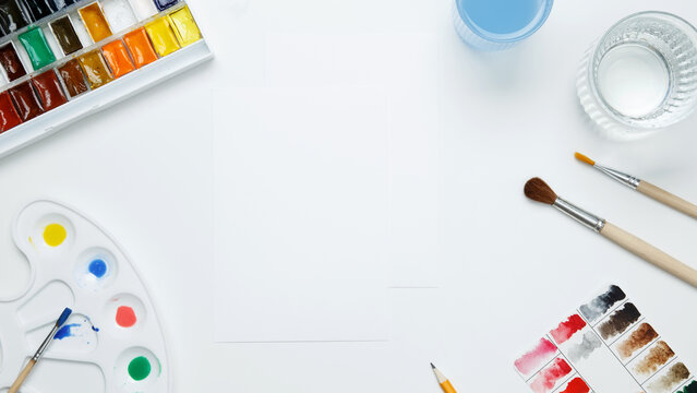Watercolor and other artistic accessories on a white background. Artist's desk workplace. Top view, copy space, flatlay