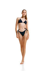 Portrait of beautiful fit woman with with perfect shape and ponytail hairstyle posing in black lingerie, swimsuit isolated studio background.