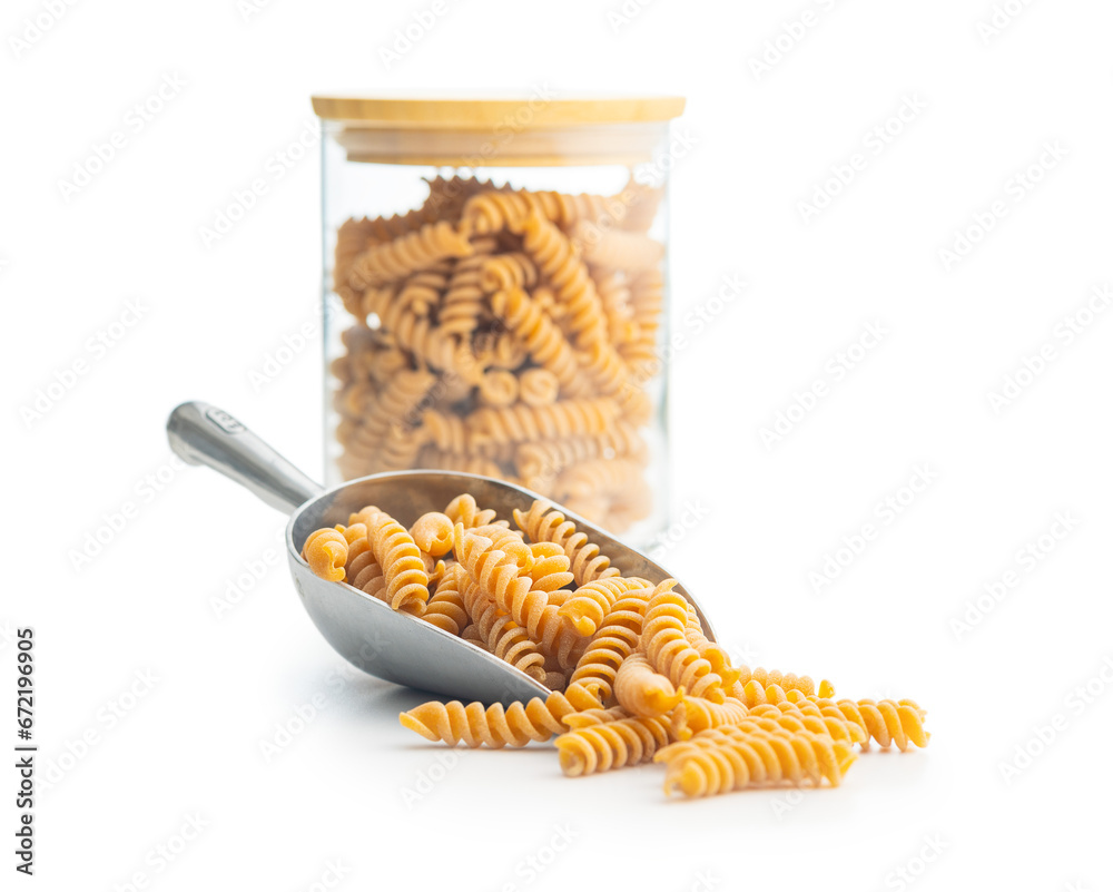 Wall mural Raw whole grain fusilli pasta. Uncooked pasta in scoop isolated on white background.