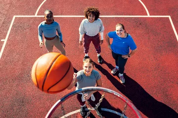 Fotobehang Portait of diverse group of young woman having fun playing basketball outdoors. © Zoran Zeremski