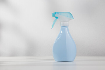 Blue spray bottle on white wooden table.