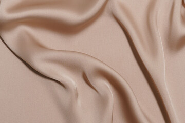 luxury crumpled and wrinkled beige polyester or synthetic fabric close-up. background for your...