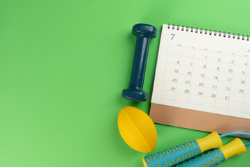 Time for exercising sport equipment and calendar on green table background