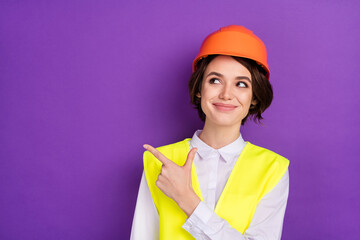 Photo of optimistic nice brunette hair lady point empty space wear builder uniform isolated on vivid purple color background