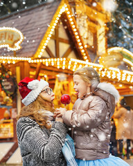 Happy mother and daughter eat a red sugar apple at the traditional German Christmas market.