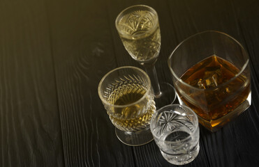 Different alcohol drinks in glass on wooden surface on dark background. Luxury elite alcohol in glass cups. Low key dark scene