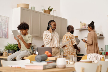 Smiling Black woman calling coworker when her son doing homework, daughter and husband cooking lunch