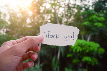 Hand-holding paper with the words 'Thank you!' handwritten on a torn piece.