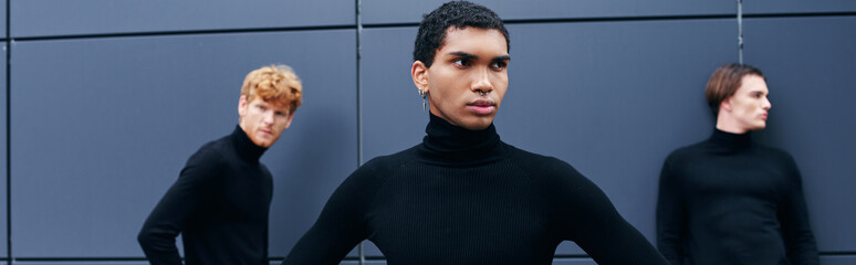 Obraz premium attractive african american man in turtleneck with earring posing in front of other men, banner