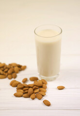 Glass of almond milk with almond nuts on white wooden table. Dairy alternative milk for detox, healthy eating and diets. Selective focus