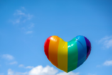Celebration of pride month, Colourful rainbow heart shaped balloon floating in blue sky as...