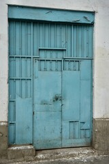 Rustic Blue metal door and agte on a concrete wall, Lima, Peru. 