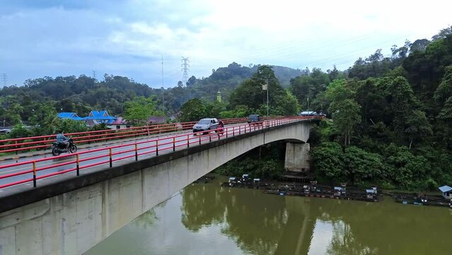 Aerial 4k video of cars passing a bridge by a River in Sumatra, Indonesia