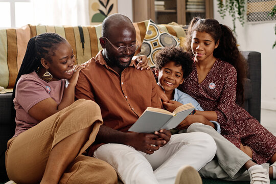 Father of family reading book on Martin Luther King Jr ideas to his wife and two kids