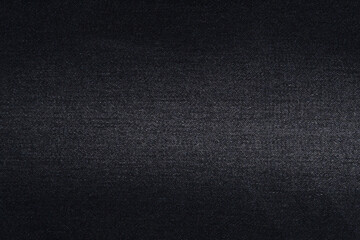 Close-up of the texture of black denim fabric with fraying. Material for making jeans. Background for your design