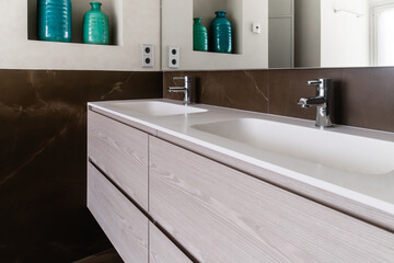 Double sink with wooden cabinet, mirror and shelf with two vases, green and blue. Concept of minimalism, cleanliness and natural light