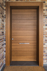Front view of front door of a house in solid wood and brick wall. Security concept