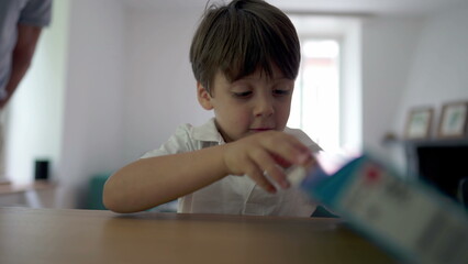 Naklejka premium One little boy opening gift box. Child receiving birthday present in eager anticipation. Kid trying to rip toy box
