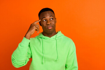 Photo of intelligent guy dressed green hoodie finger on head thoughtfully look empty space think...