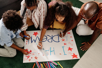 Parents and their two kids drawing I have a dream placard together