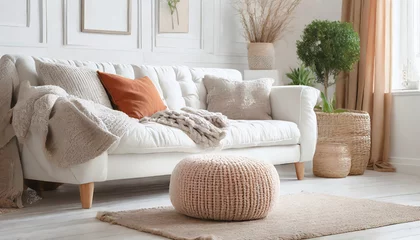Foto op Canvas Knitted pouf near white fabric sofa with blanket and terra cotta pillows Scandinavian hygge style home interior design of modern © Martin