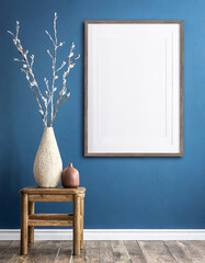 Wood side table, vase with twigs near big empty frame mock up poster with copy space against blue wall. Scandinavian home interior design of modern living room. - obrazy, fototapety, plakaty