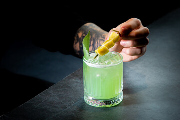 green cocktail with lime in a glass glass with ice and pieces of fruit, side view