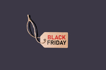 Brown cardboard tag with string, on a black background with red and black letters that say: 'Black Friday'. Concept of black Friday, offers, promotion, cheap prices, sales and consumerism.