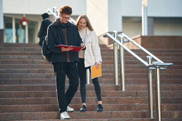 Front view, walking the stairs. Two young students are together outdoors