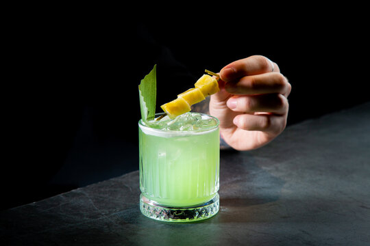 green cocktail with lime in a glass glass with ice and pieces of fruit, side view