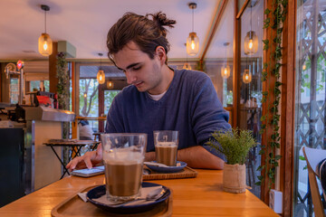 Fototapeta na wymiar man drinking coffee in cafe with warm lighting 