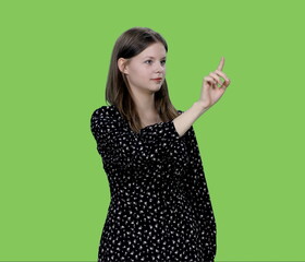 Young charming woman makes finger touching virtual display on green background, Chroma key