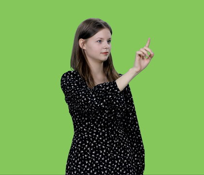 Young charming woman makes finger touching virtual display on green background, Chroma key - Powered by Adobe