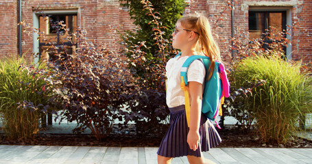 Rear view of schoolgirl goes to school in morning, pupil rushes to classes. Back to school