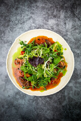 meat gravy with meat, cherry tomatoes and a bunch of greens on top, top view