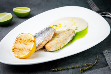 pieces of fried fish with sauce and fried lemon on a white plate side view