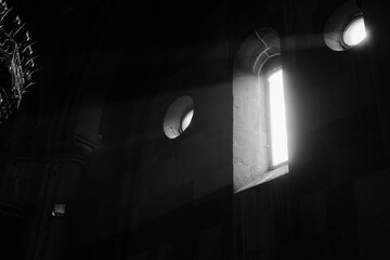 Grayscale of sunlight streams through a window in a church