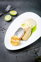 pieces of fried fish with sauce and fried lemon on a white plate side view