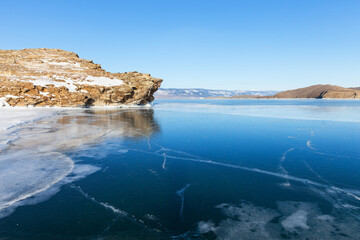 Frozen Baikal Lake in January sunny day. View of Small Sea and blue clear ice of Olkhon Gate Strait. Beautiful winter landscape. Ice travel and outdoor recreation. Winter natural background
