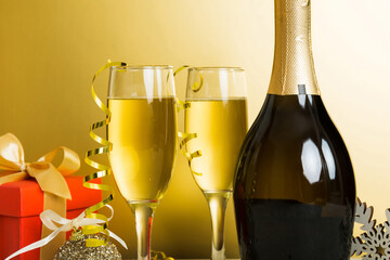 Champagne bottle with confetti, glasses and christmas decor on colored holiday background. Flat lay New Year decorations